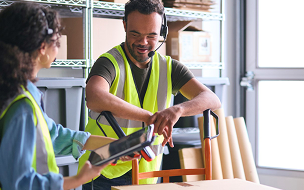 A women holding an iPad speaks to someone in a high visibility vest