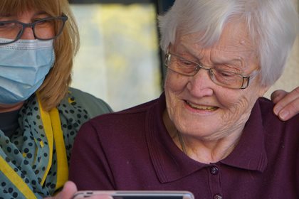 A women and a senior watch something on a phone