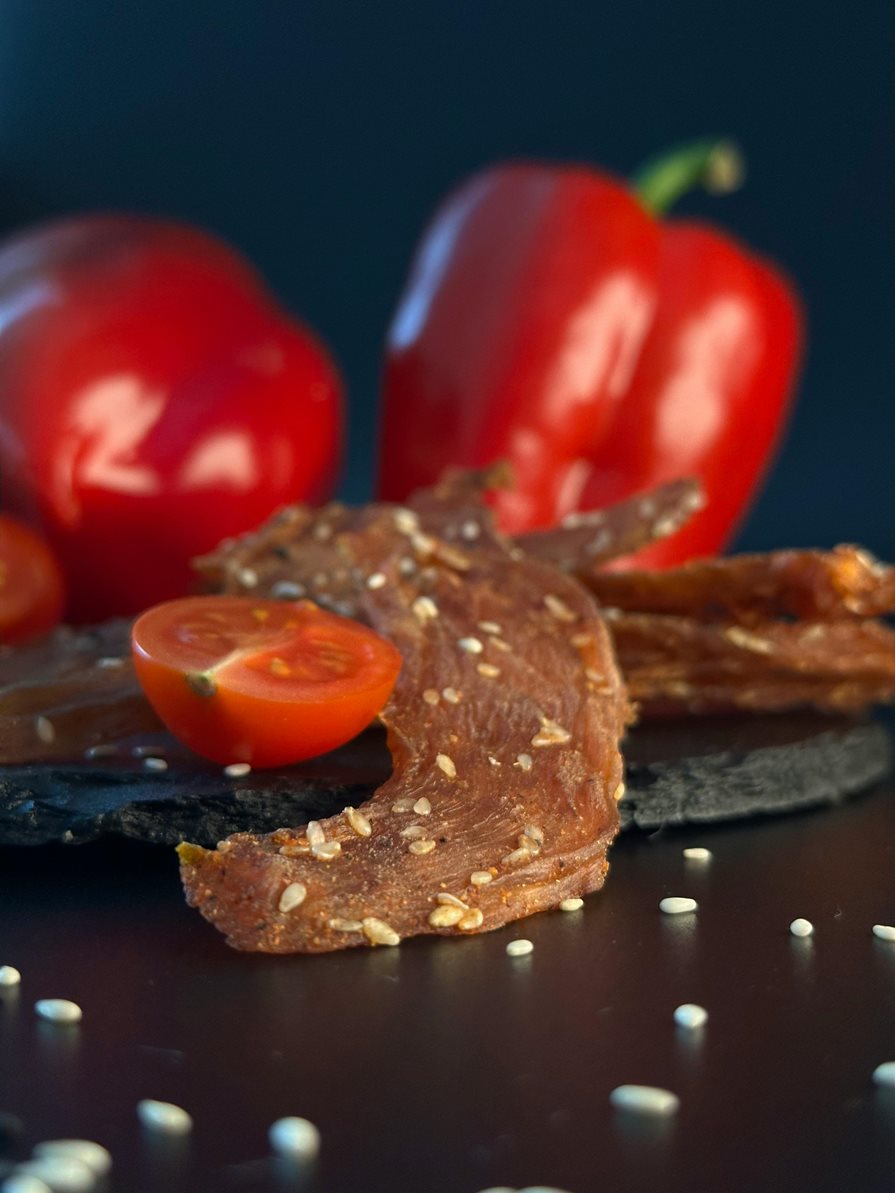 Jerky on a table with a paper and tomato