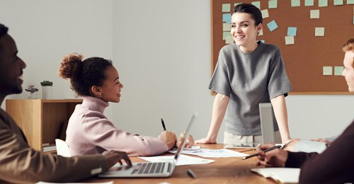 a person stands at a table while others work in a group