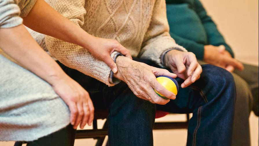 A nurse holding a senior's hand