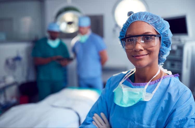 Female surgeon wearing scrubs and protective glasses in procedure room.