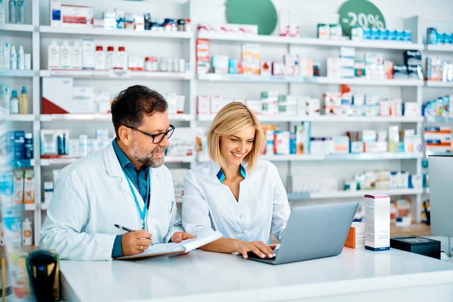 Two providers looking at computer in pharmacy.
