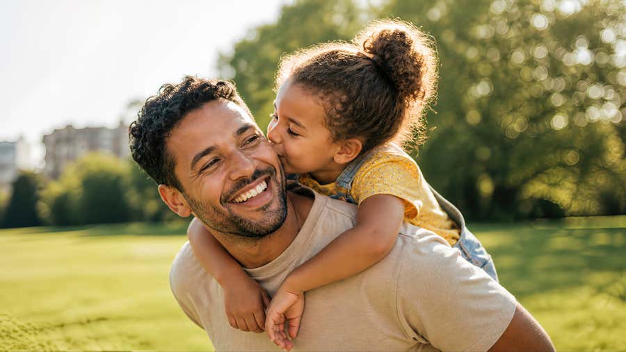 Dad carries his daughter on his back.
