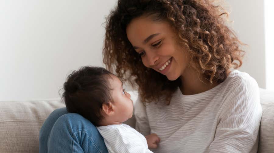 A woman holding a baby on her lap and smiling.