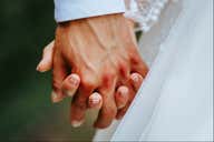 Close-up of two hands with white dress visible.
