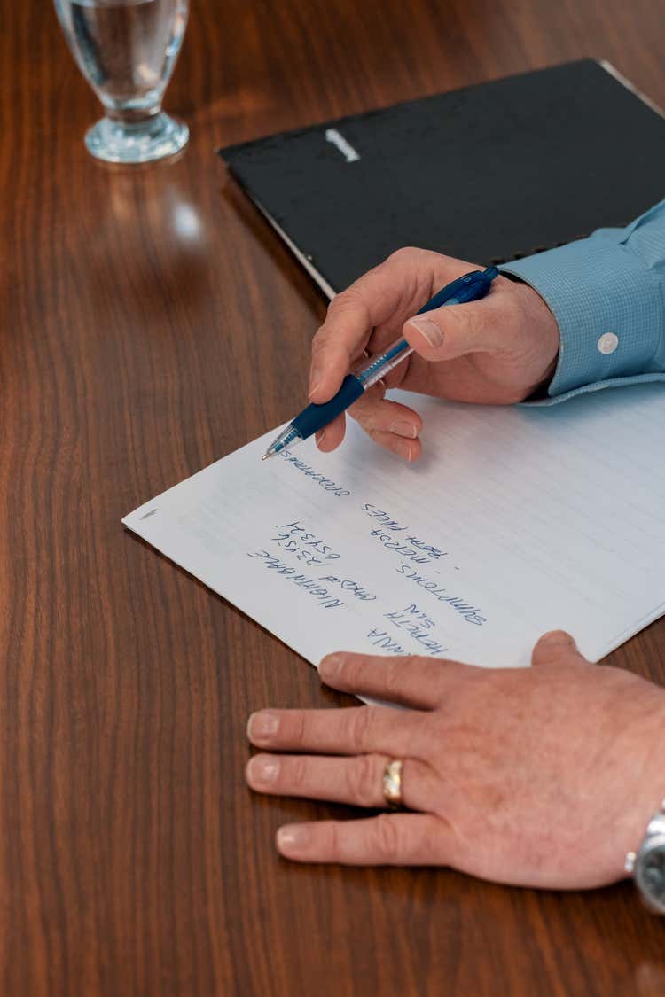 A person writing on lined paper with a blue pen.